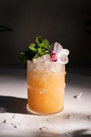 Mai Thai Cocktail glacé, décoré avec une fleur et de la menthe, sur fond neutre.